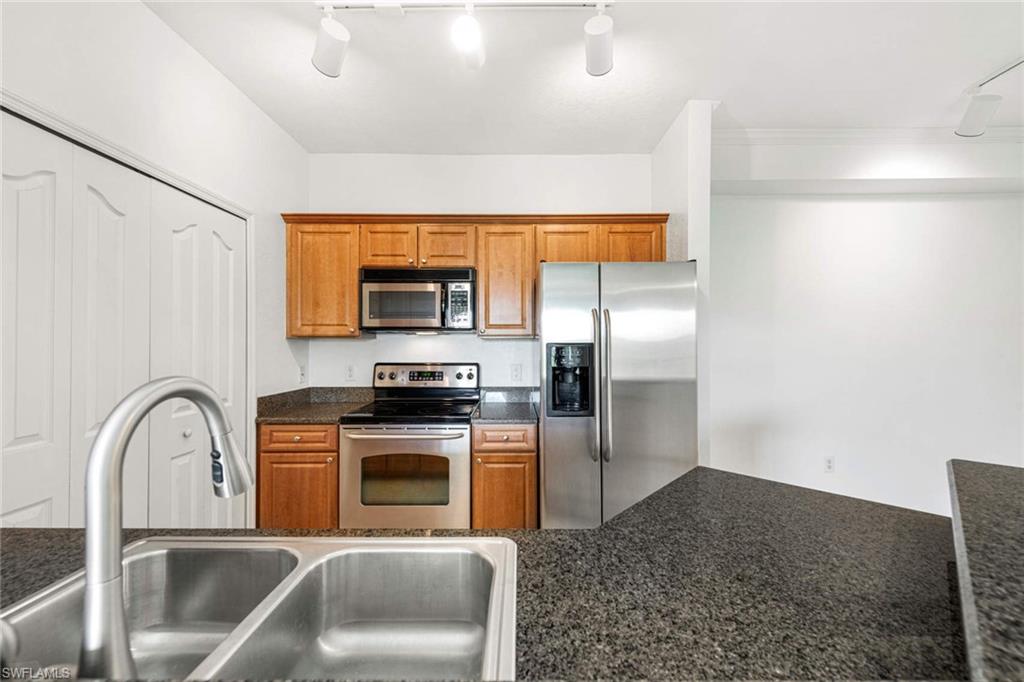 12980 Positano Circle, Unit 308 Naples, FL 34105 - Photo 9 of 22 a kitchen with stainless steel appliances granite countertop a refrigerator a stove and a sink with wooden floor