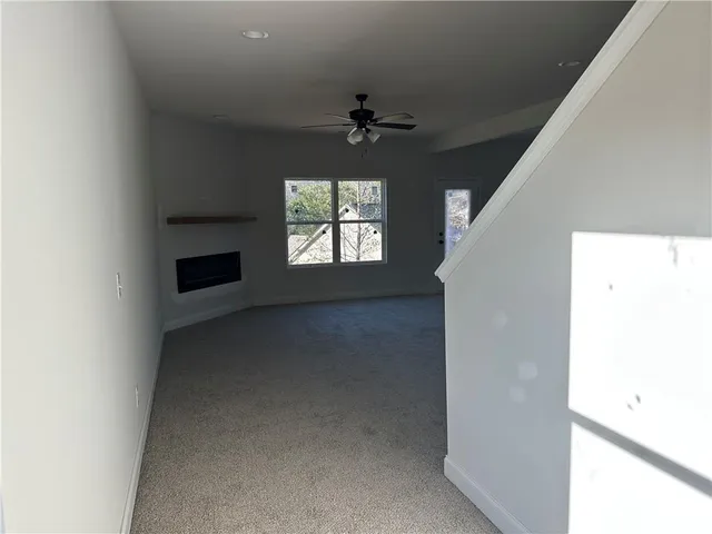 an empty room with windows and ceiling fan