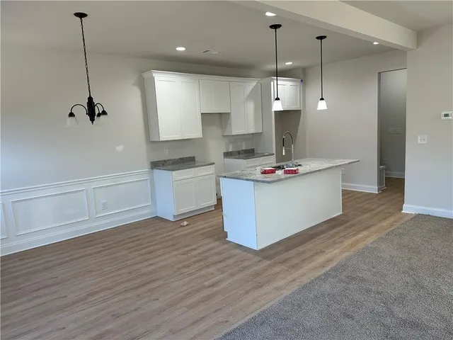 a kitchen with stainless steel appliances granite countertop a sink a stove a refrigerator and a wooden floor