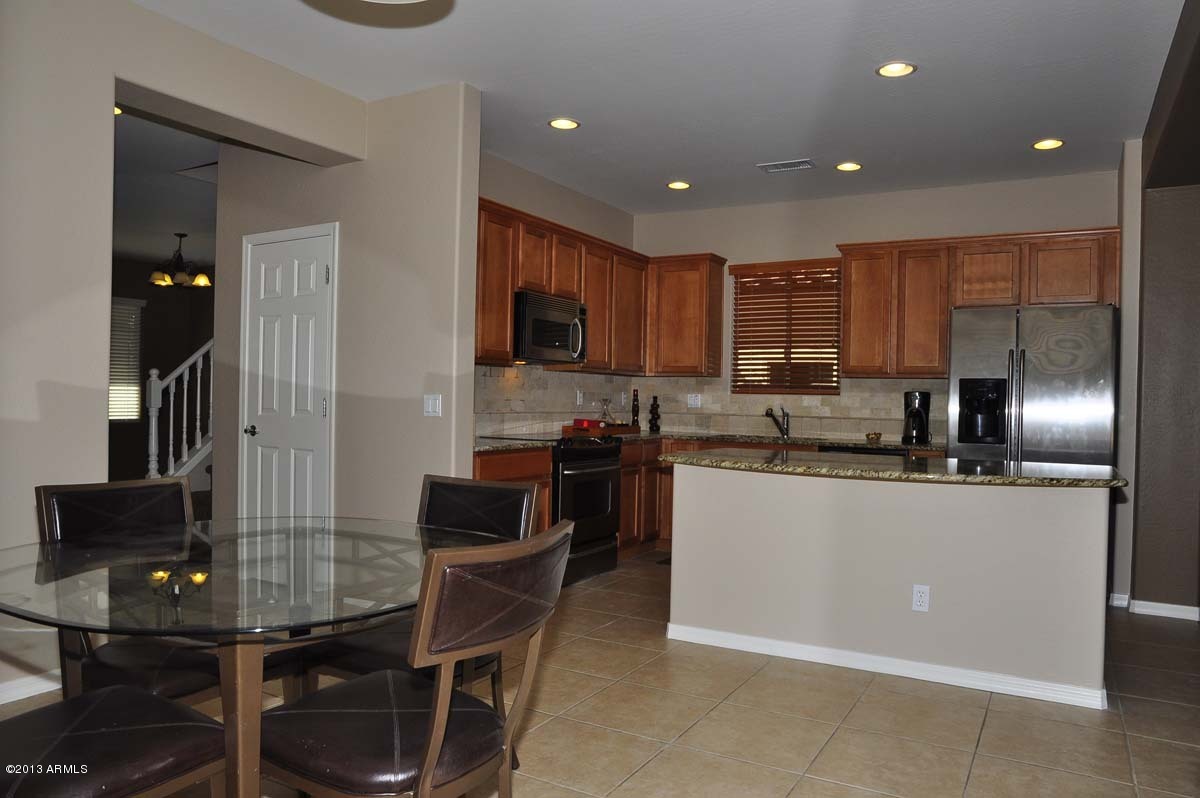 20798 West Ridge Road Buckeye, AZ 85396 - Photo 13 of 47 a kitchen with stainless steel appliances granite countertop a sink counter space and a refrigerator