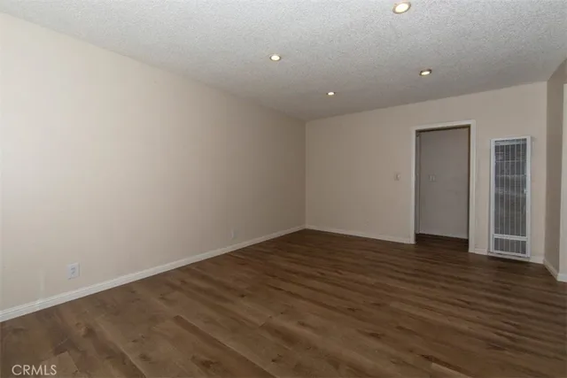 a view of an empty room with wooden floor and closet