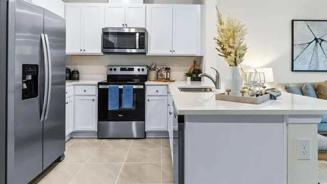 a kitchen with stainless steel appliances granite countertop a refrigerator a stove top oven a sink and cabinets