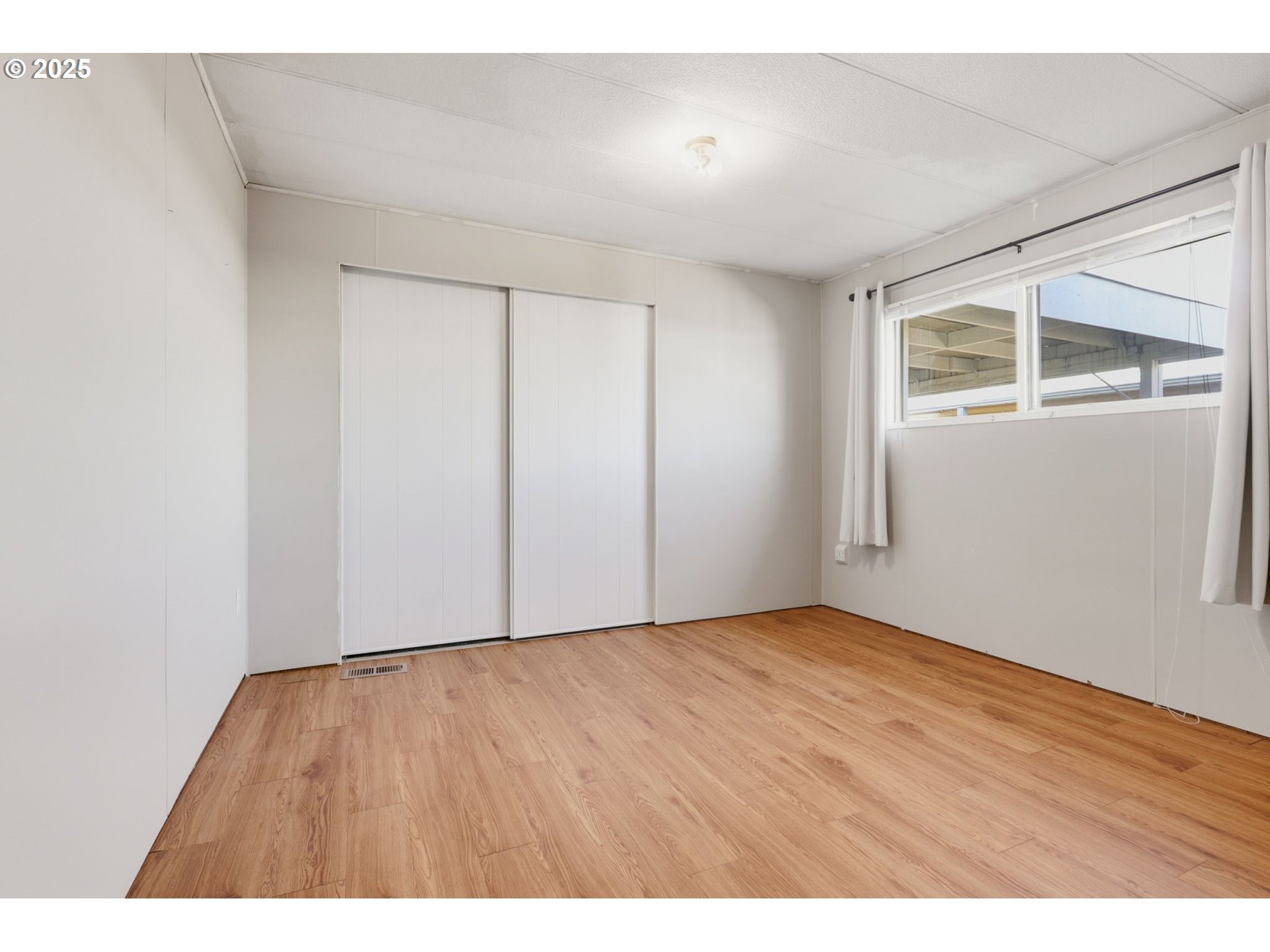 2902 East 2nd Street, Unit 67 Newberg, OR 97132 - Photo 24 of 38 a view of an empty room with wooden floor and a window