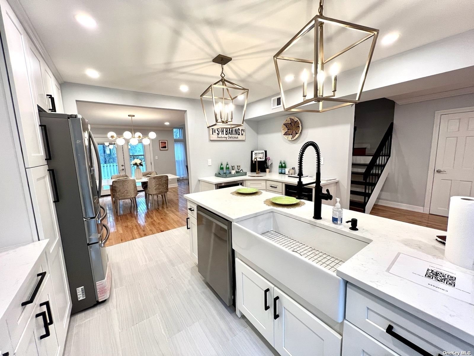 a large kitchen with stainless steel appliances a sink a counter space and a view of living room