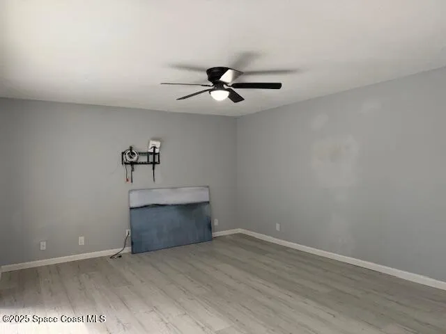 wooden floor in an empty room with a chandelier fan