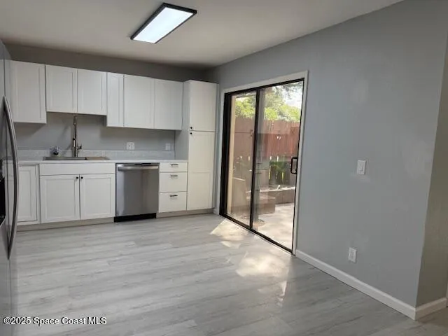 a large kitchen with a stove a sink dishwasher a refrigerator and white cabinets with wooden floor