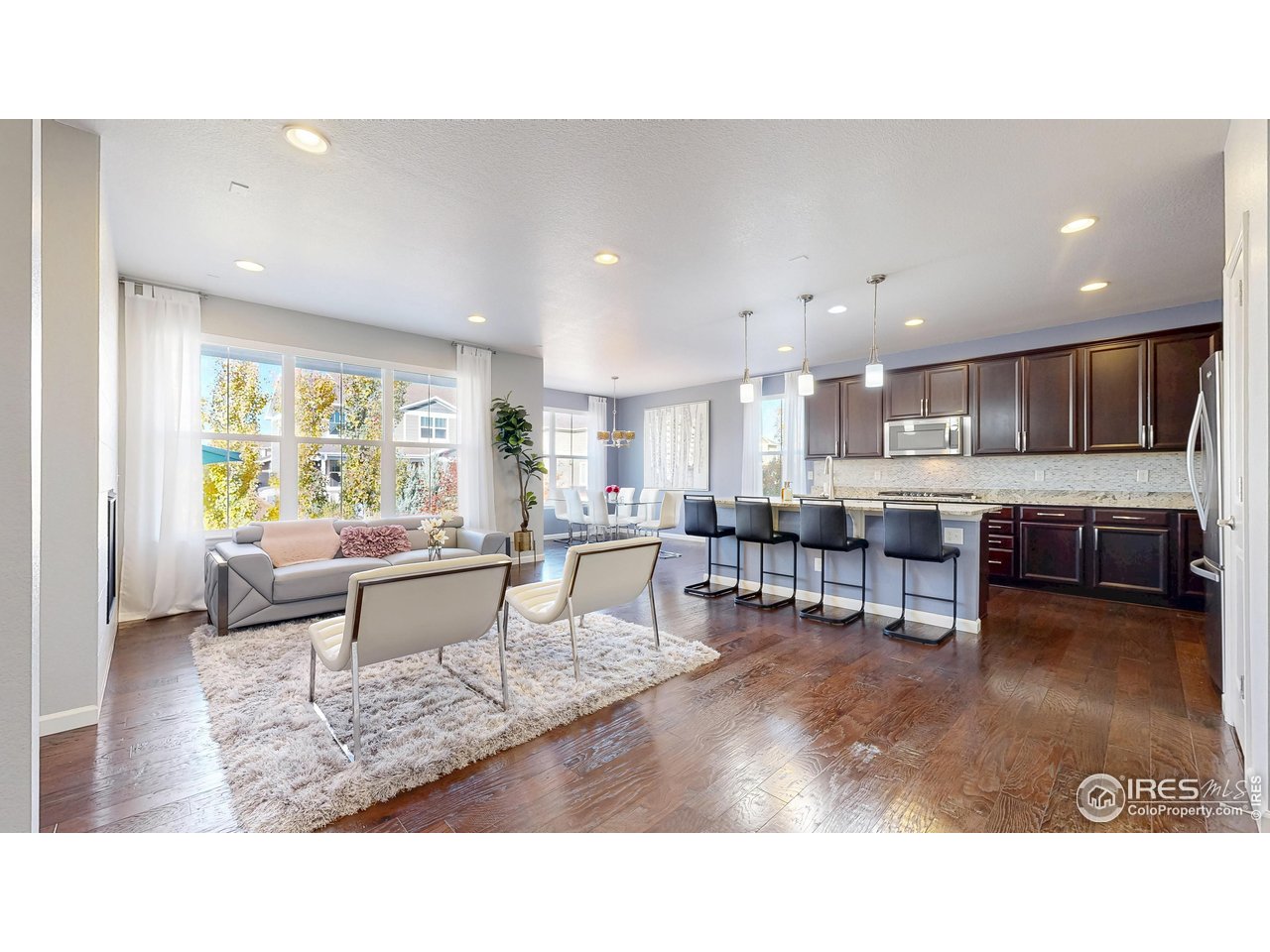 6794 Spring Rain Road Timnath, CO 80547 - Photo 3 of 49 a living room with stainless steel appliances kitchen island granite countertop a living room and couches with kitchen view