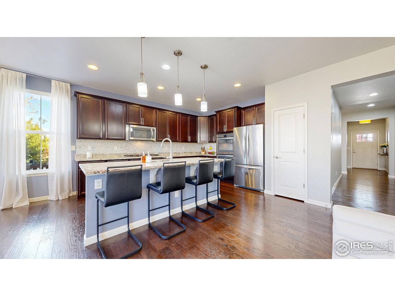6794 Spring Rain Road Timnath, CO 80547 - Photo 9 of 49 a kitchen with a dining table chairs refrigerator and window