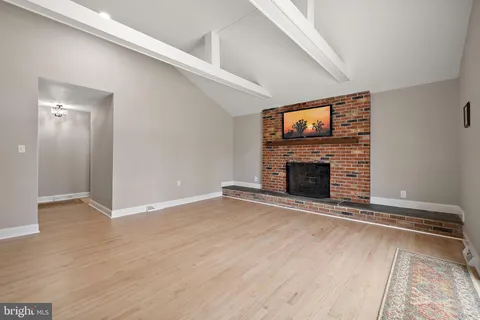 an empty room with wooden floor fireplace and windows