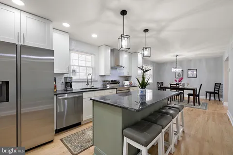 a kitchen with kitchen island a counter top space a sink stainless steel appliances and cabinets