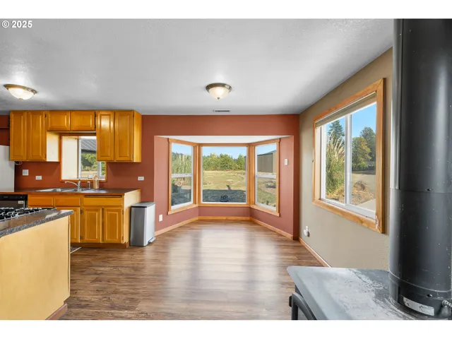 a open kitchen with wooden floor a sink and a large window