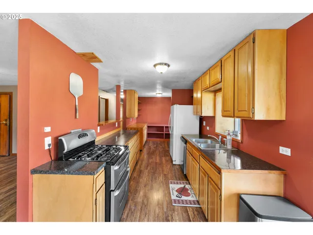 a kitchen with stainless steel appliances granite countertop a stove a sink dishwasher and cabinets with wooden floor