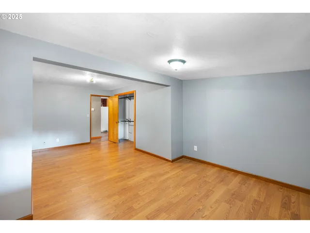 a view of an empty room with window and wooden floor