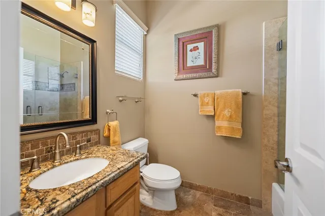 a bathroom with a granite countertop toilet a sink and mirror