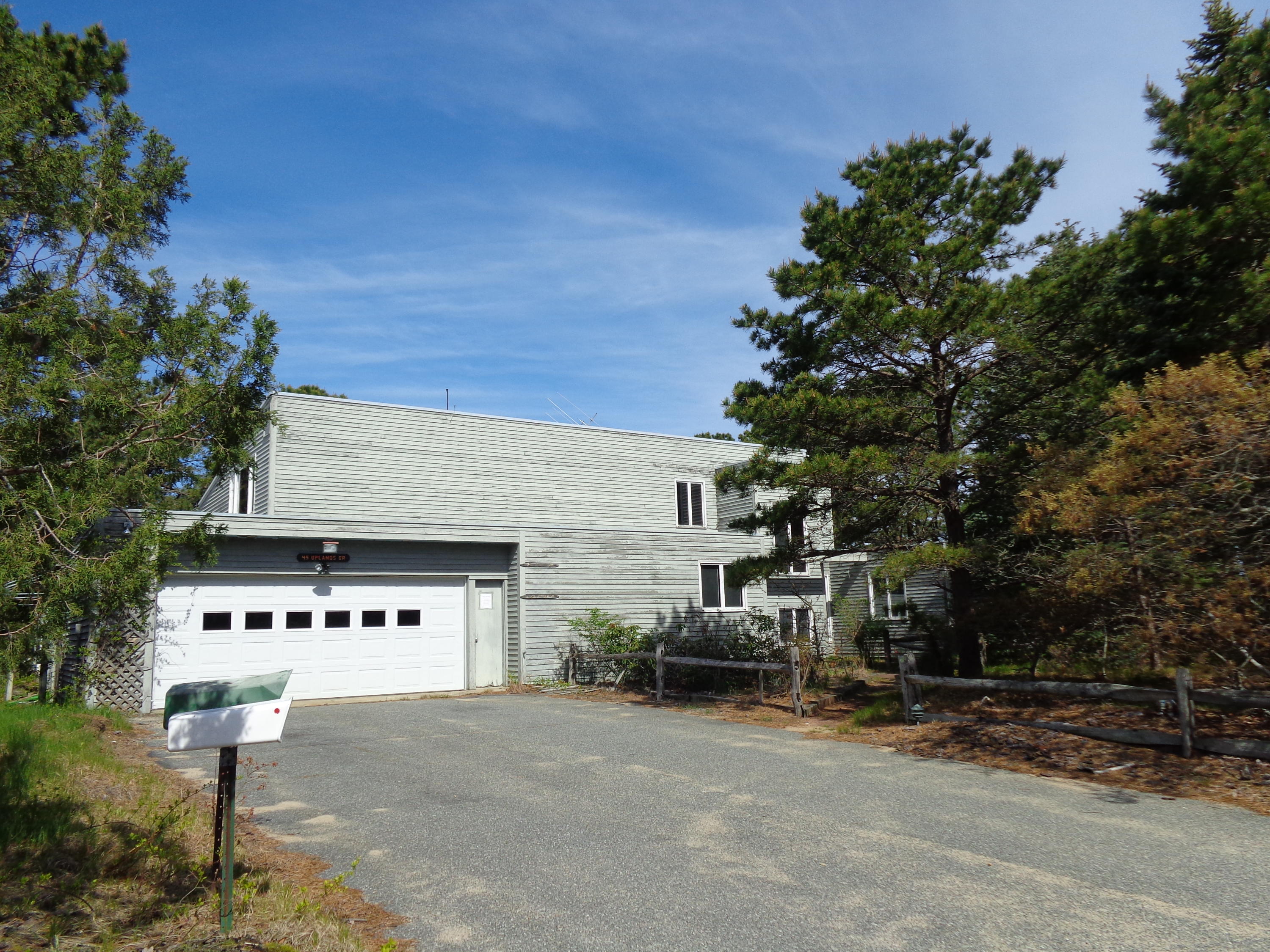 a front view of a house with street and trees