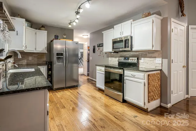a kitchen with granite countertop white cabinets and white appliances