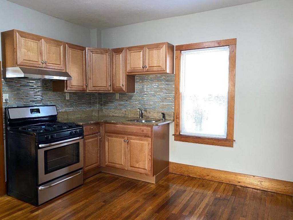 a kitchen with granite countertop wooden floors and stainless steel appliances