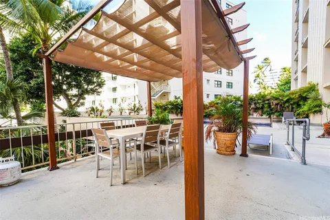 a view of a patio with table and chairs potted plants and large tree