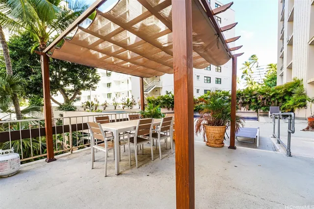 a view of a patio with table and chairs potted plants and large tree