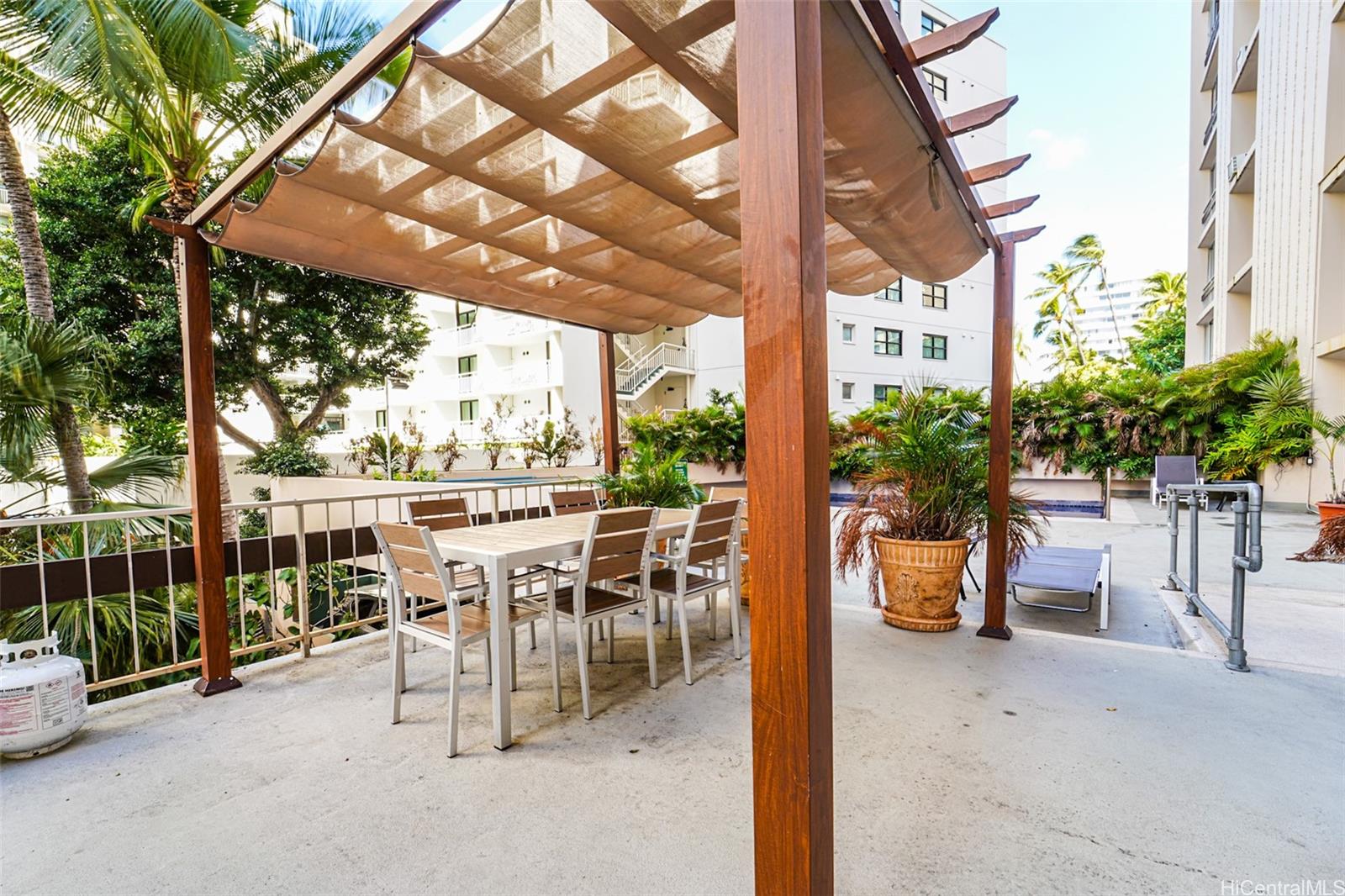 431 Nāhua Street, Unit 309 Honolulu, HI 96815 - Photo 20 of 25 a view of a patio with table and chairs potted plants and large tree