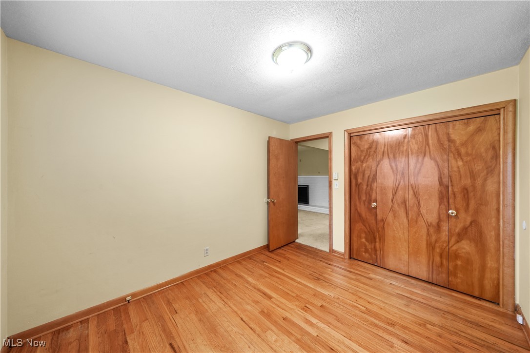 10 Kehner Road Mogadore, OH 44260 - Photo 15 of 32 Unfurnished bedroom with a textured ceiling, a closet, and light hardwood / wood-style flooring