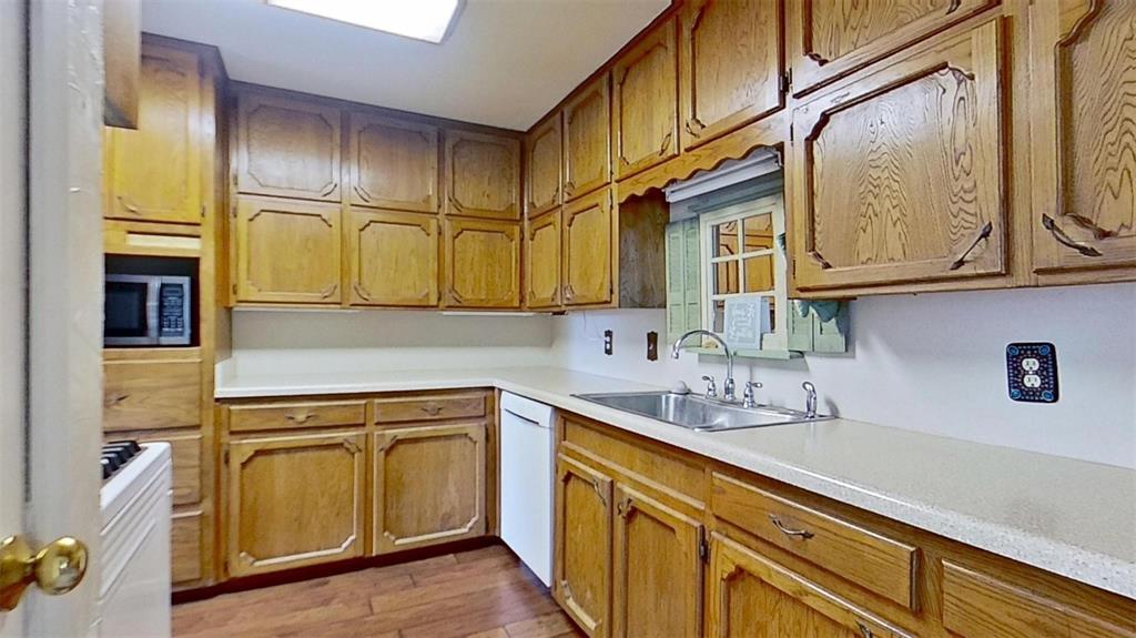 900 Silver Creek Azle Road Azle, TX 76020 - Photo 8 of 27 Kitchen featuring wood cabinetry, light-toned countertops, an undermount sink, and wood-finish flooring