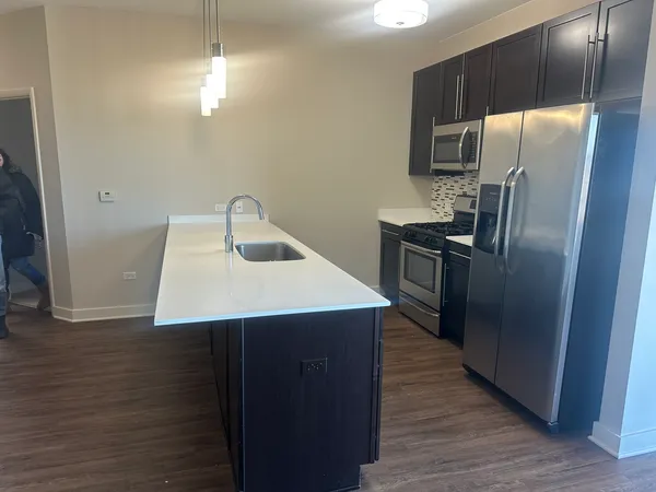 a kitchen with kitchen island a counter space a sink appliances and cabinets