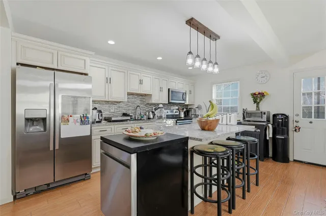 a kitchen with stainless steel appliances a table chairs refrigerator and microwave