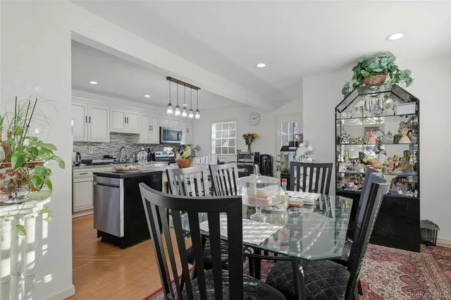 a open kitchen with stainless steel appliances granite countertop a stove a refrigerator a kitchen island a sink dishwasher a dining table and chairs with wooden floor