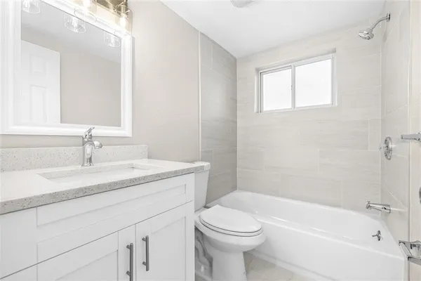 a bathroom with a granite countertop sink a toilet and shower