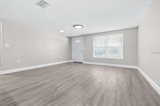 an empty room with wooden floor and windows