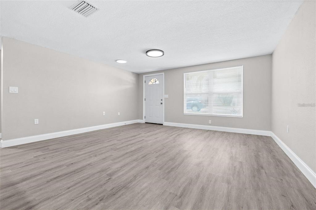 13926 Helen Avenue Hudson, FL 34667 - Photo 3 of 44 an empty room with wooden floor and windows