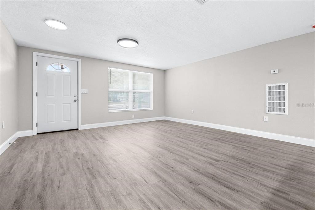 13926 Helen Avenue Hudson, FL 34667 - Photo 4 of 44 an empty room with wooden floor and windows