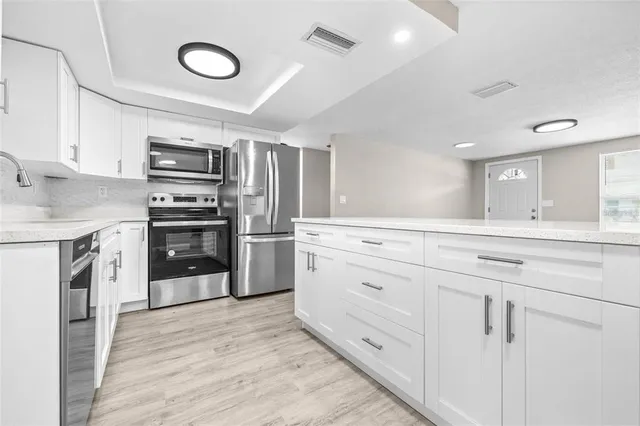 a kitchen with cabinets stainless steel appliances and wooden floor