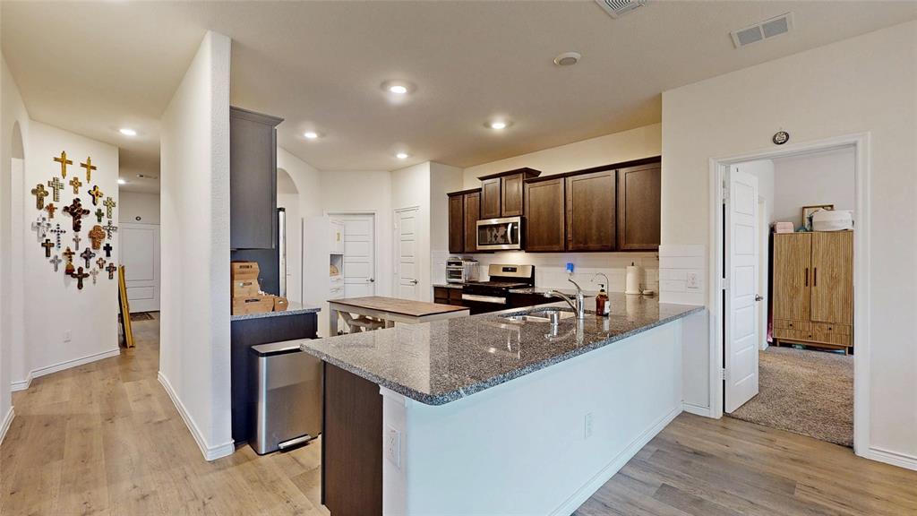 4005 Glastonbury Road McKinney, TX 75071 - Photo 7 of 39 a kitchen with granite countertop a refrigerator and a stove top oven