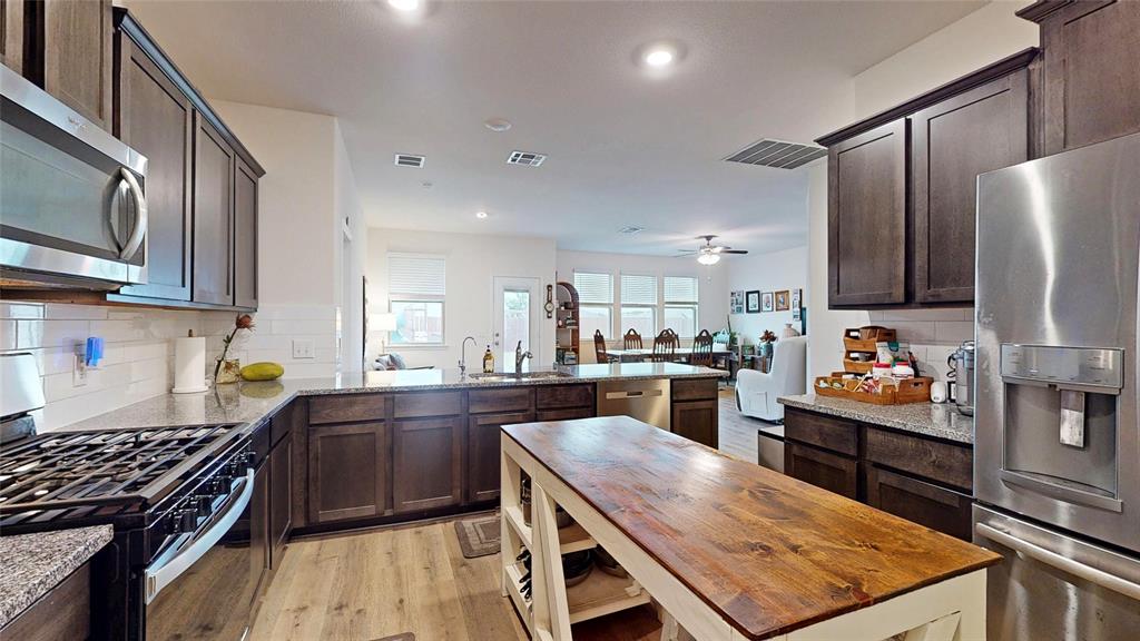 4005 Glastonbury Road McKinney, TX 75071 - Photo 10 of 39 a kitchen with stainless steel appliances granite countertop a stove top oven a sink dishwasher and a refrigerator with wooden floor