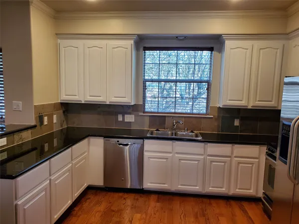 a kitchen with granite countertop white cabinets and a sink
