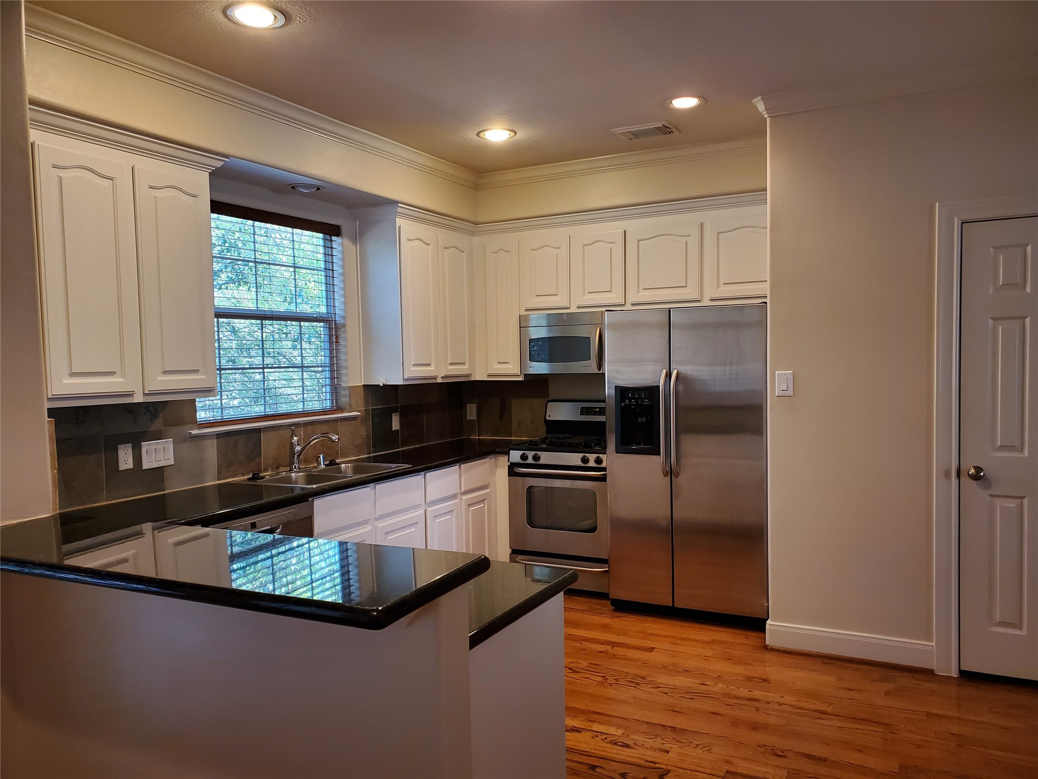 326 Malone Street Houston, TX 77007 - Photo 13 of 25 a kitchen with granite countertop kitchen island stainless steel appliances a refrigerator a sink a stove a microwave and cabinets