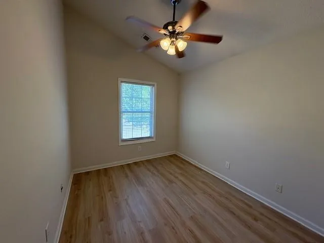 an empty room with a window and a fan