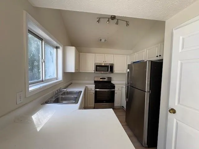 a kitchen with a refrigerator a stove top oven and cabinets