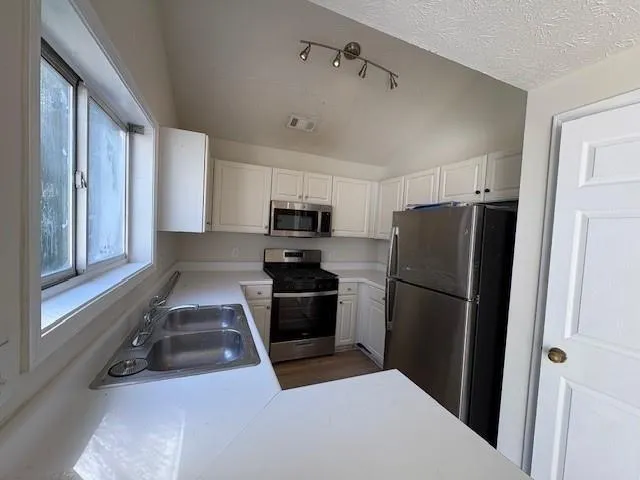 a kitchen with a refrigerator a stove top oven and cabinets