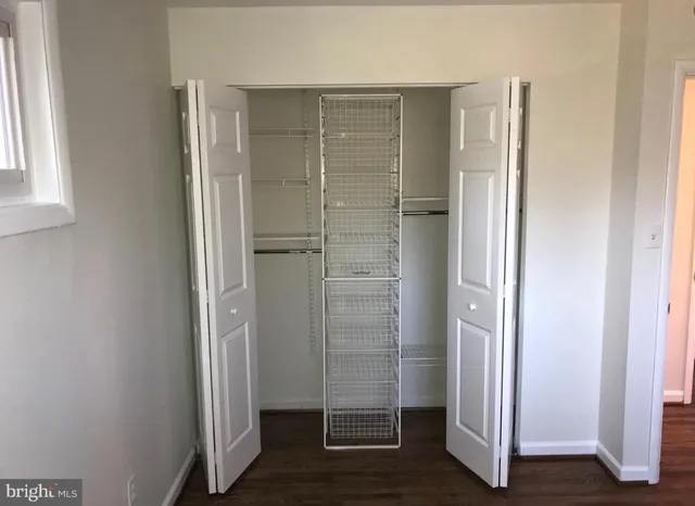 a view of an empty room with wooden floor and closet
