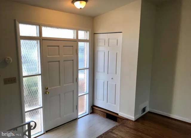 an empty room with wooden floor cabinet and windows