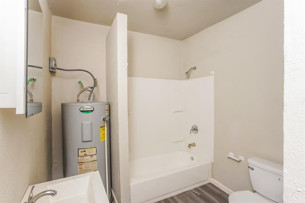 2402 Summer Avenue Waco, TX 76708 - Photo 15 of 15 Bathroom featuring a white shower-over-tub combination, a toilet, a sink with a chrome faucet, and wood-finish flooring