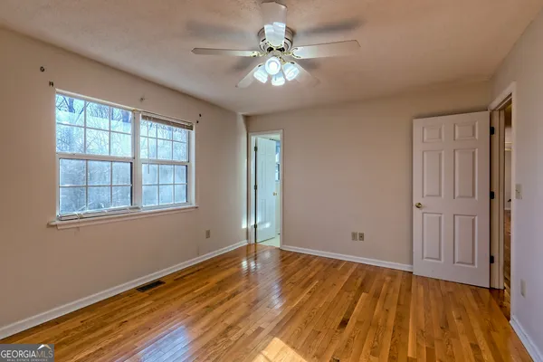 a view of an empty room with window and chandelier fan