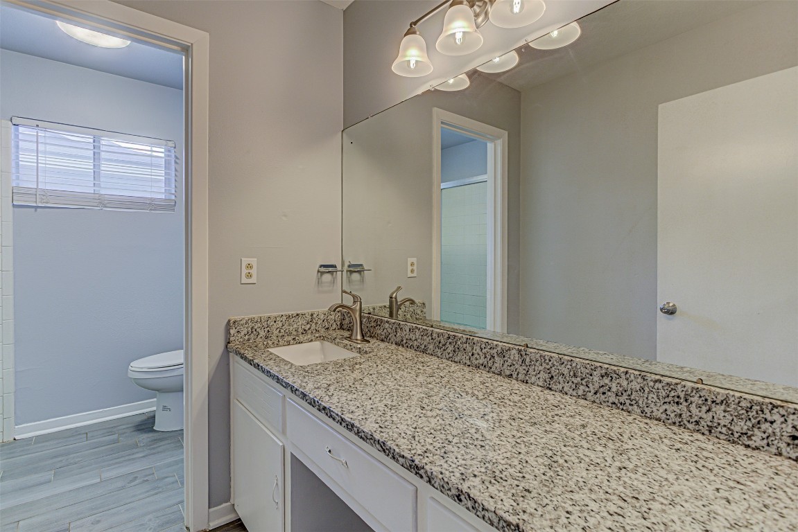 2001 Oakglen Drive Austin, TX 78745 - Photo 34 of 40 a bathroom with a granite countertop sink a toilet and a mirror
