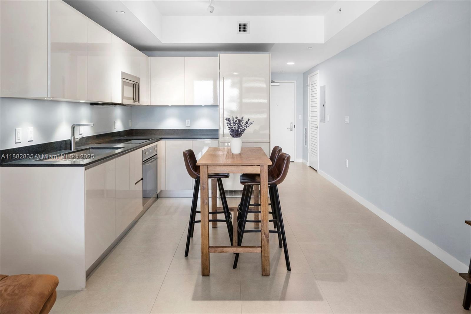 1010 Brickell Avenue, Unit 3610 Miami, FL 33131 - Photo 14 of 37 a kitchen with stainless steel appliances kitchen island a table chairs in it and wooden floors