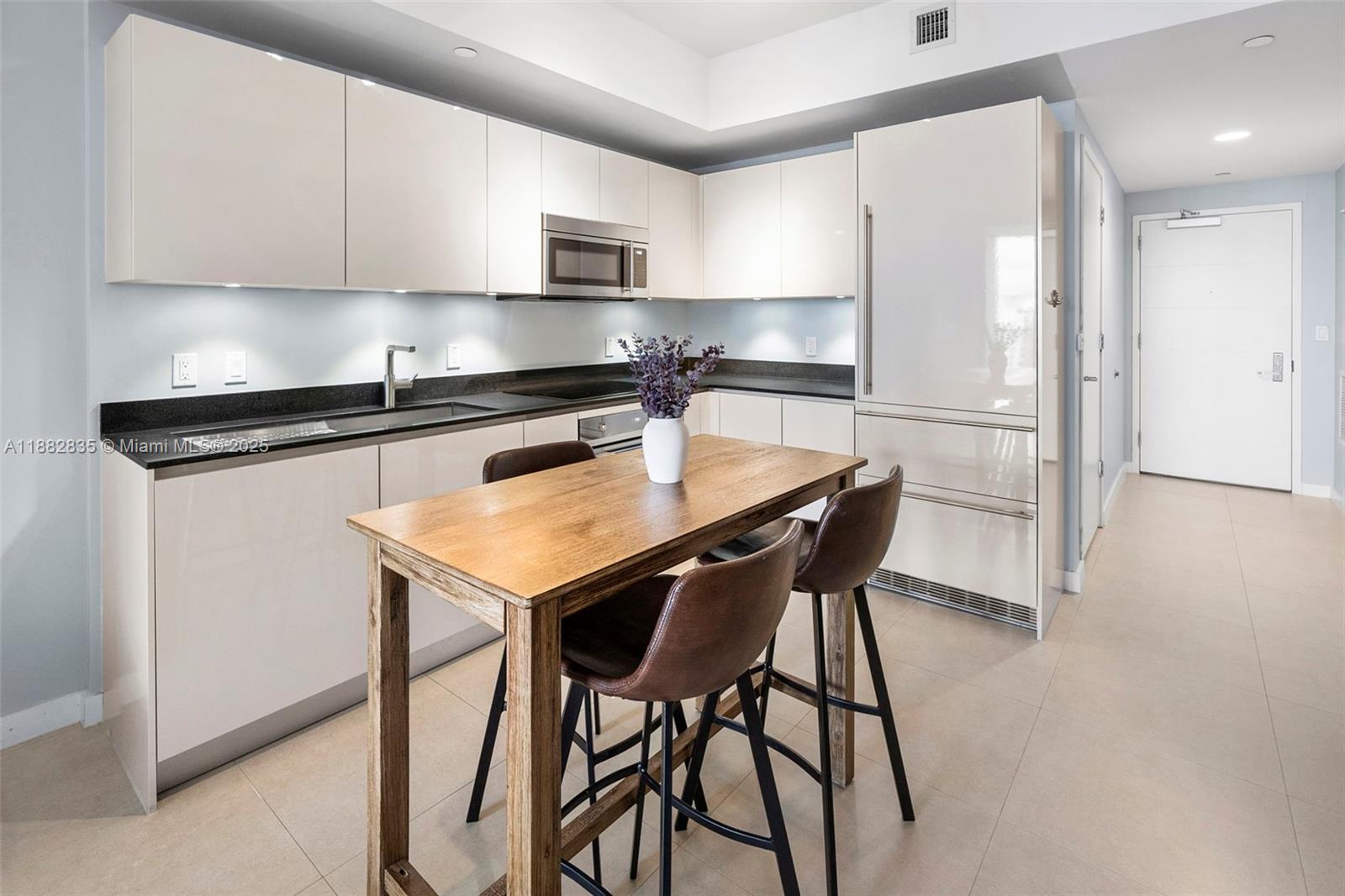 1010 Brickell Avenue, Unit 3610 Miami, FL 33131 - Photo 18 of 37 a kitchen with stainless steel appliances granite countertop a stove a refrigerator a microwave a sink and white cabinets with wooden floors