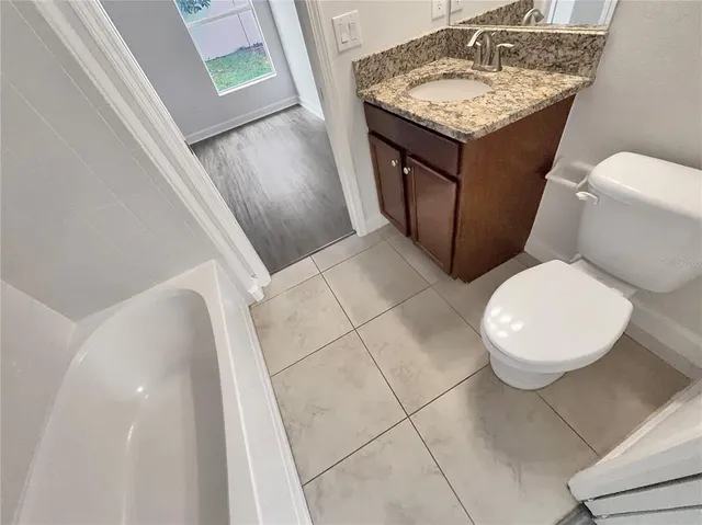 a bathroom with a granite countertop sink and a toilet