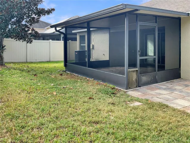a backyard of a house with plants and large tree